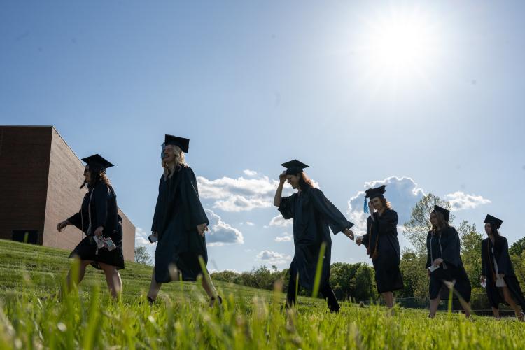 grads wearing caps and gowns walk outside