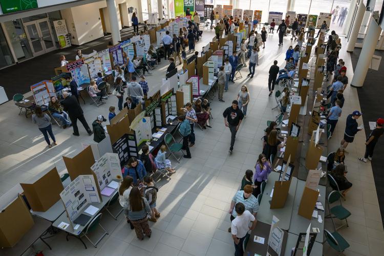 An ovehead image of people standing next to three long rows of exhibits at the Regional Science Day event at Ohio University