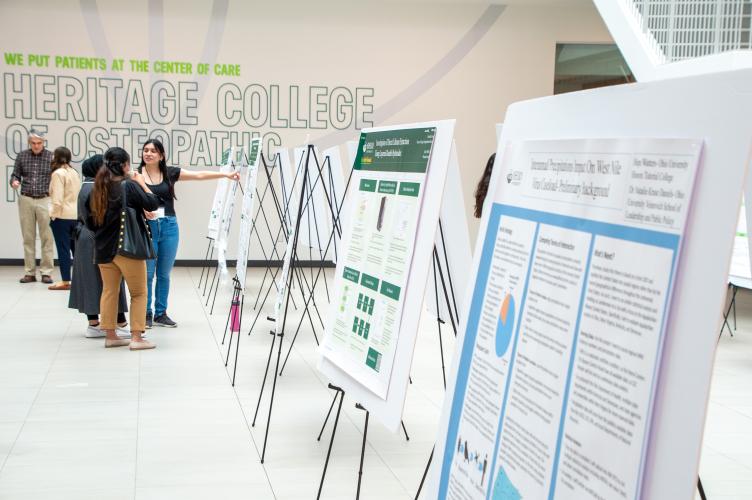Students look at research posters at the Summer Research Symposium