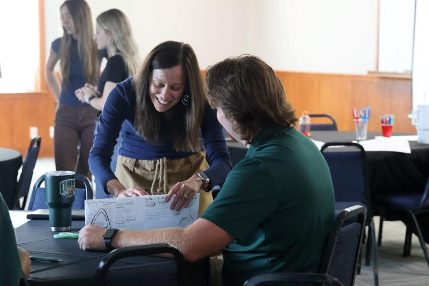 Female professor working with male college student on art project instruction techniques