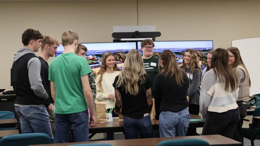 group of students standing in a cirle around a table