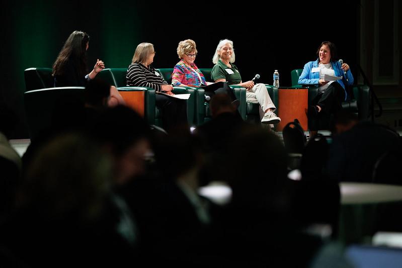 Five panelists sit on stage and talk at the State of the Region Conference