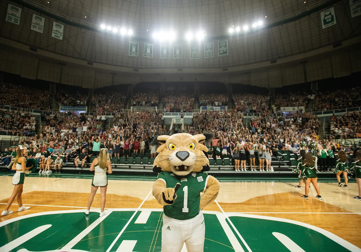 Rufus points at the camera while standing in front of cheerleaders and first-year students during the New Student Convocation in the Convocation Center