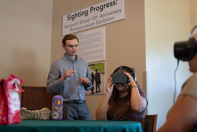 Two people try on virtual reality equipment while an instructor stands nearby