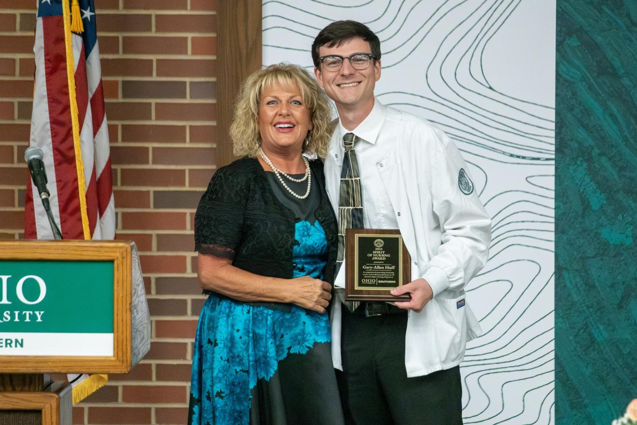 Kade Huff holds a nursing award while standing with an OHIO representative