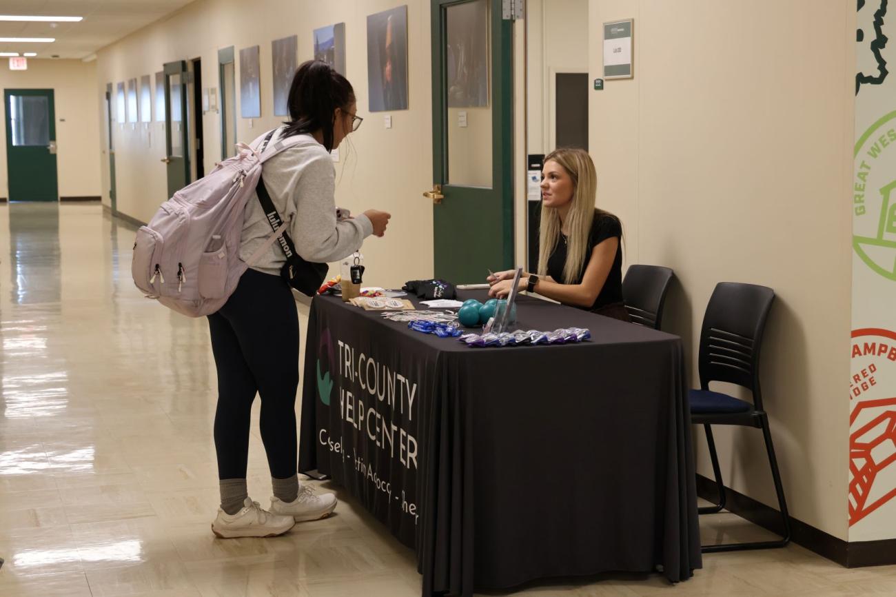 Female sitting at table, talking to a student who is asking a question