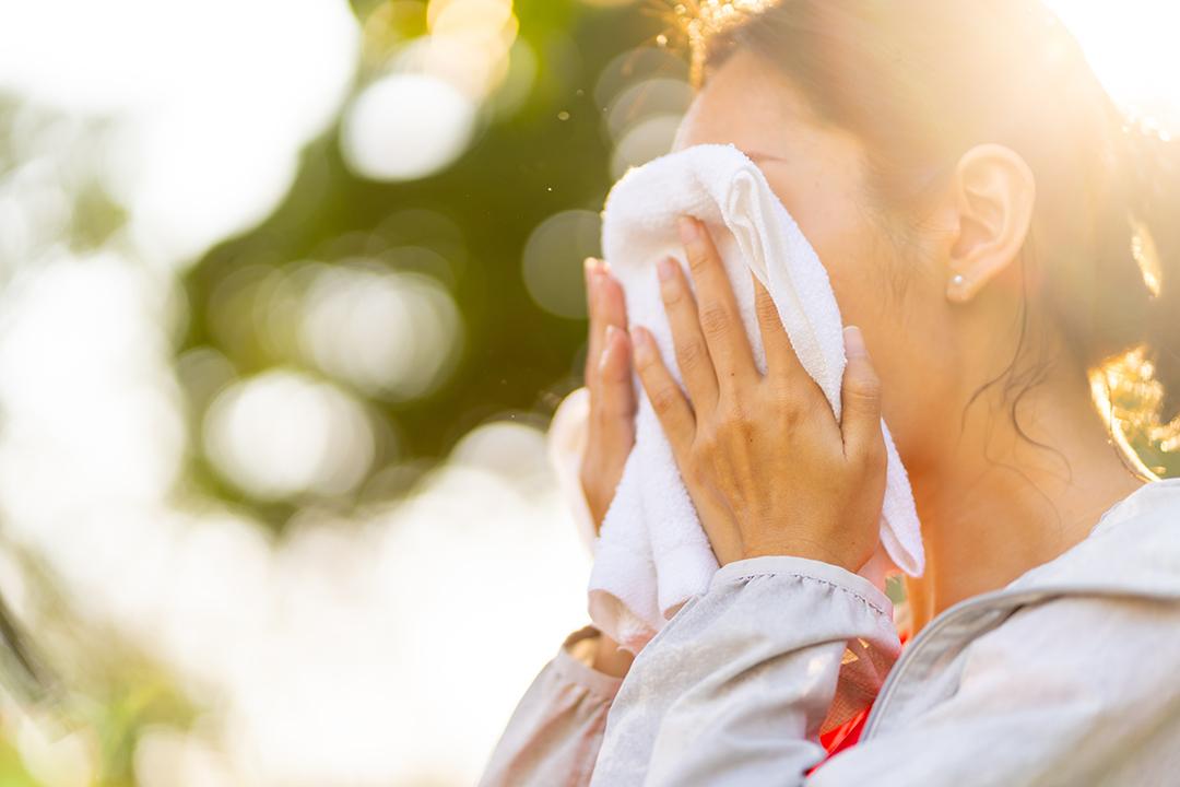 Person sweating and holding rag to their head stock image.
