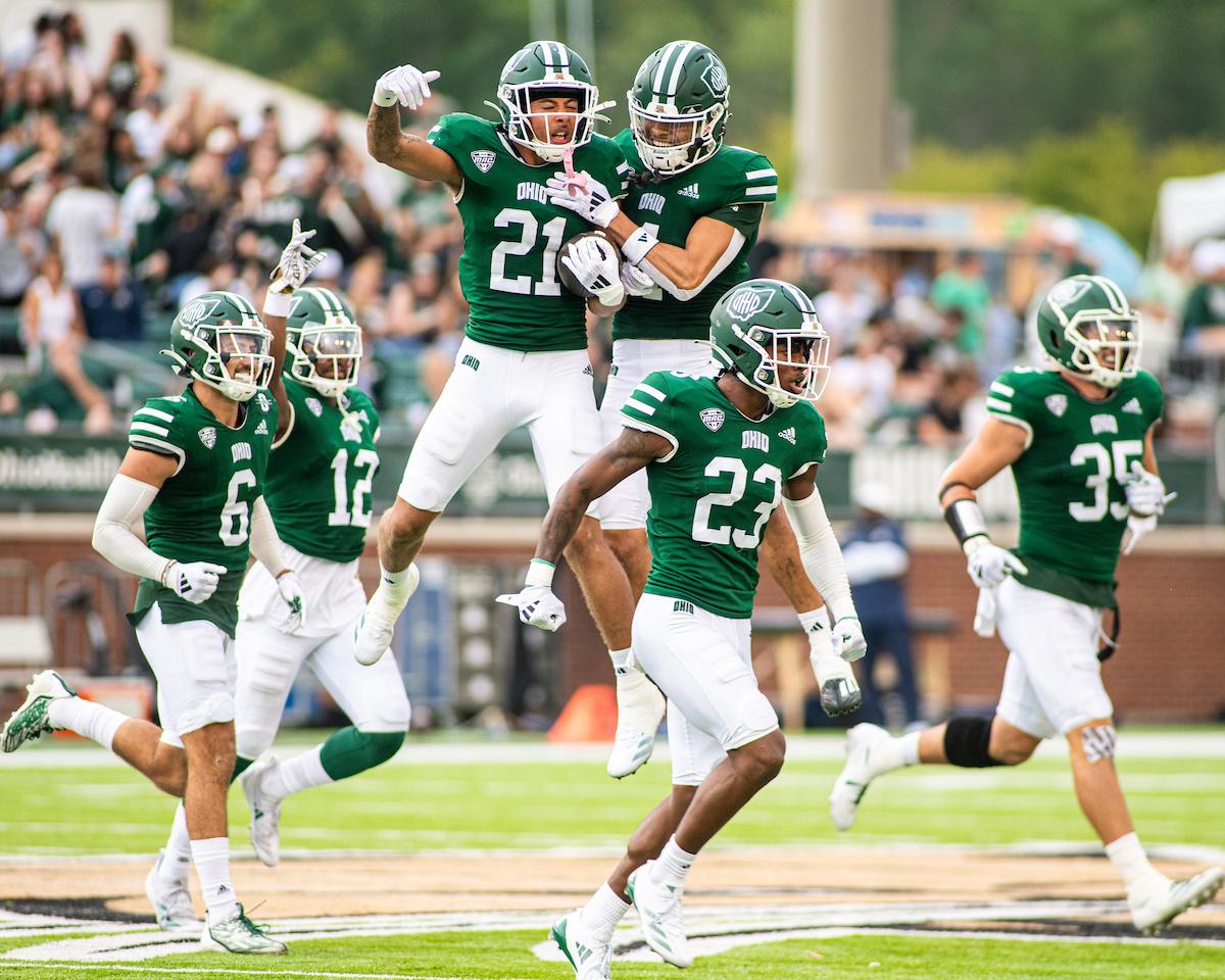 OHIO football players leap into the air and run across the field at the 2024 Homecoming Football Game