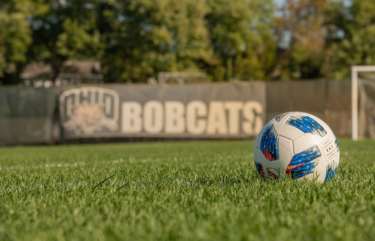 A soccer ball is shown on the grass at the soccer stadium,  and the wall in the background says OHIO Bobcats