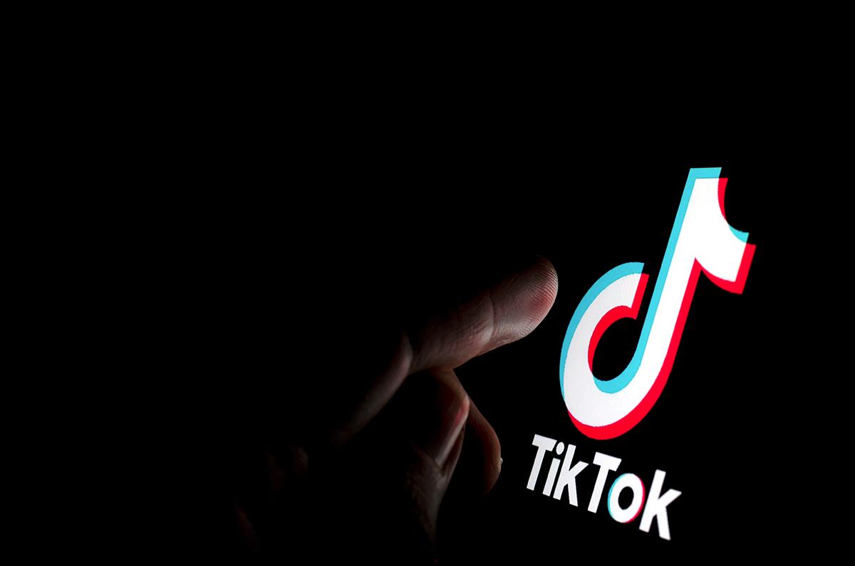 TikTok logo with a finger reaching to touch it