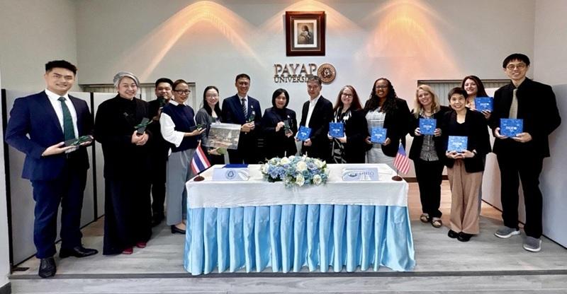 Representatives from Ohio University and Payap University stand together around a table at Payap University