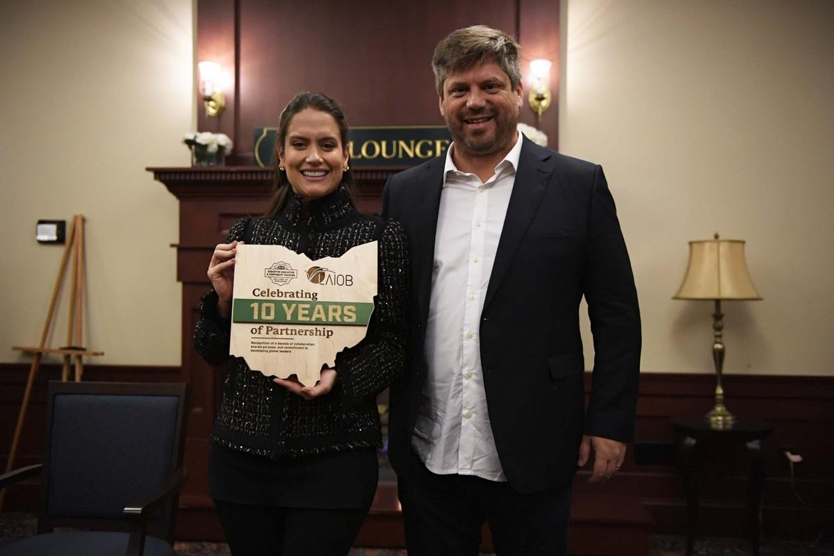 Two representatives of the OHIO - LAIOB partnership stand together and hold a plaque shaped like the state of Ohio that says "Celebrating 10 Years of Partnership"