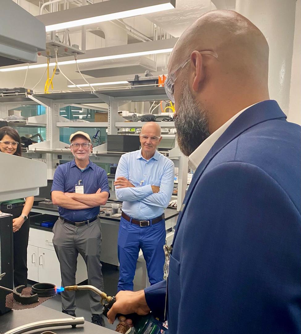 Al-Majali (far right) demonstrates a burn test of a 3D-printed carbon–carbon composite during a DOE and industry visit.