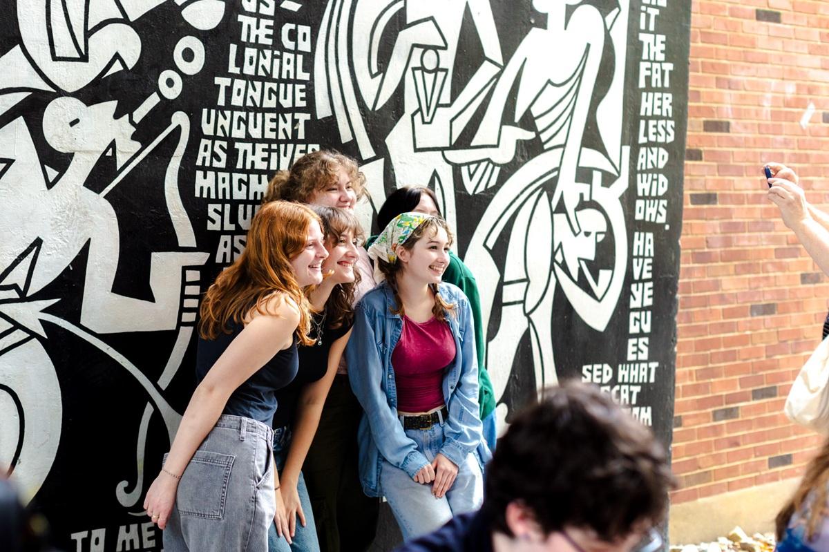 OHIO students pose for a photo while standing next to the art wall at Siegfred Hall