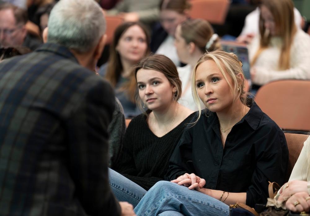 Two students listen intently to a speaker