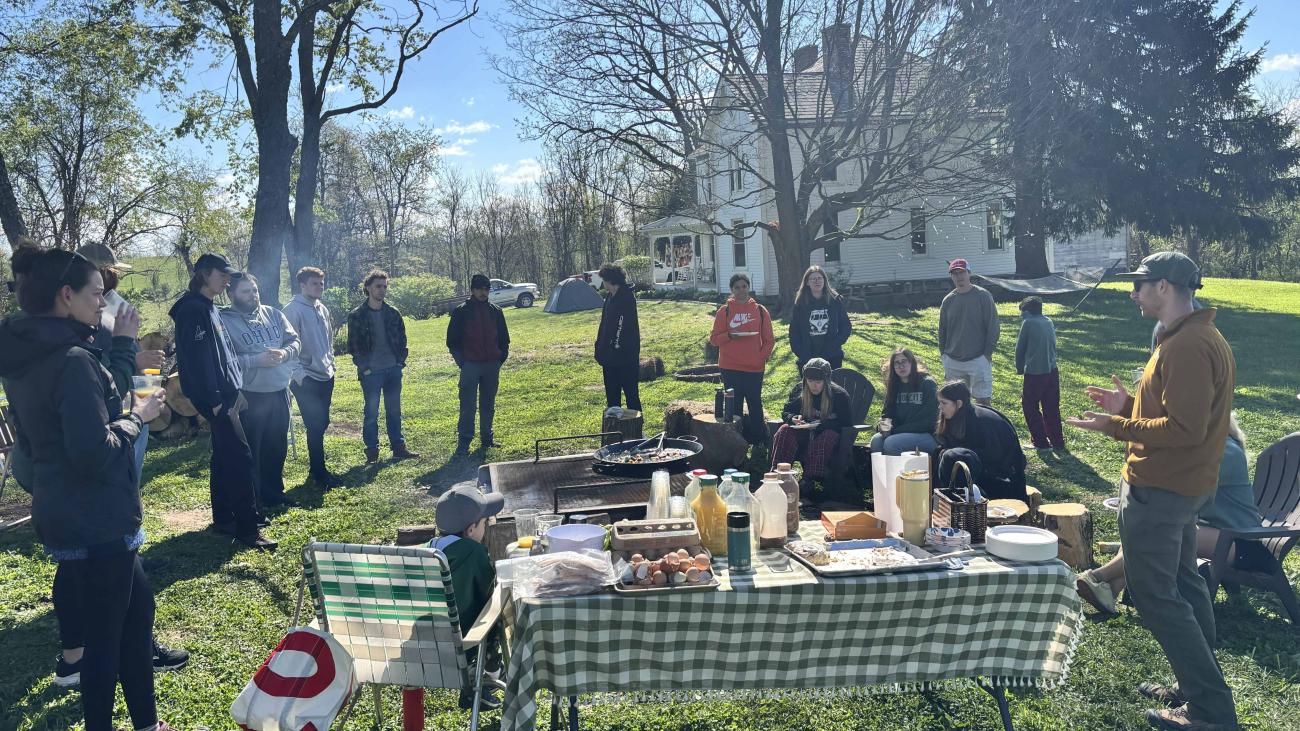 Ohio University College Students, Faculty, and Community Partners sitting around campfire