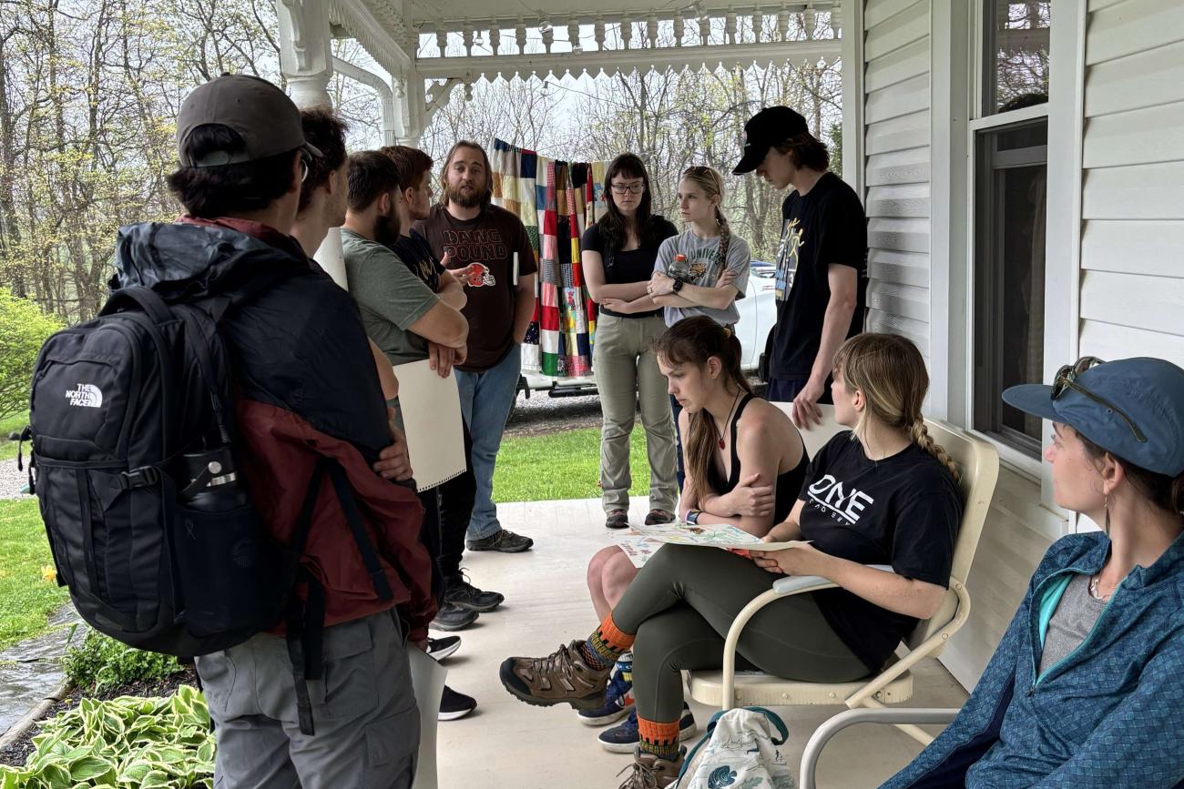Ohio University Students standing and sitting on a porch, having a conversation at Dysart Woods