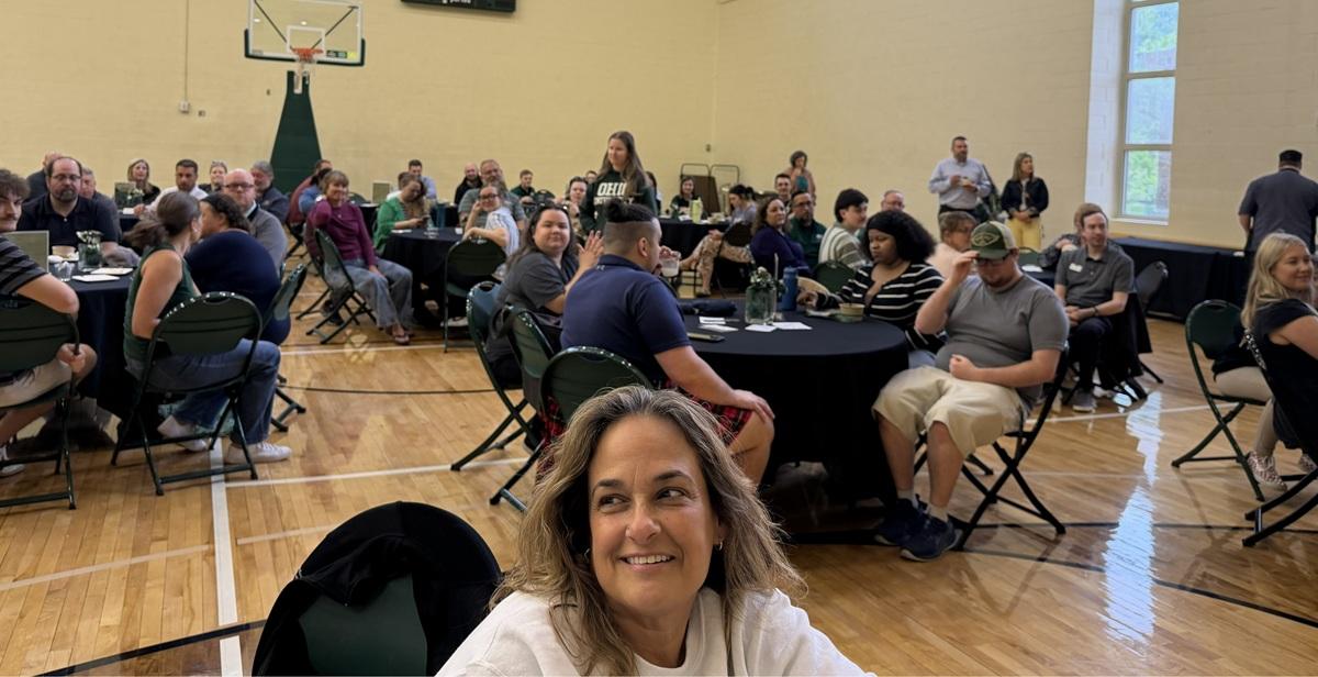 Student Affairs staff members sit at tables in the Ping Recreation Center during the event