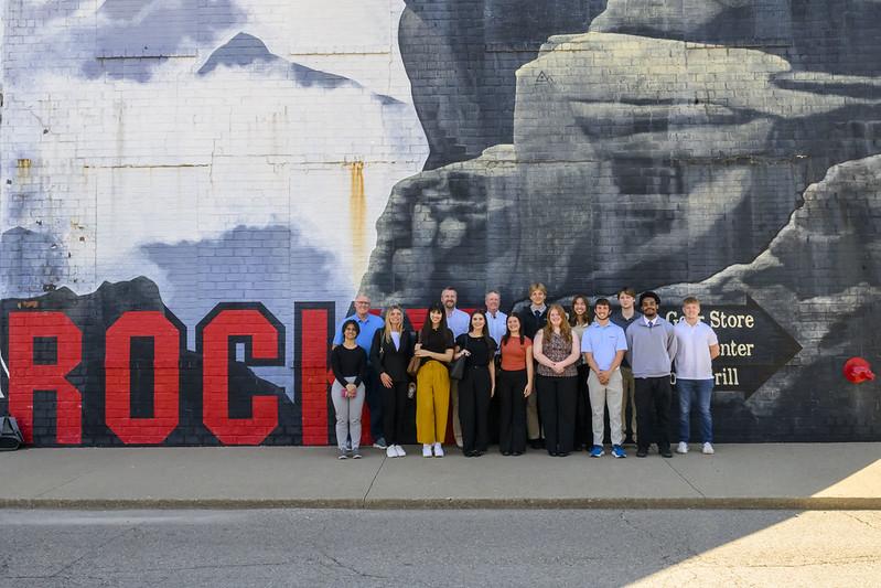 A group of interns and program officials stand outside a Rocky Boots building that has the word "Rocky" painted on  it