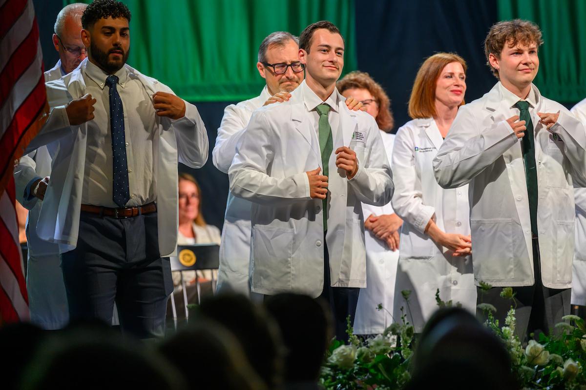HCOM students receive their white coat on stage