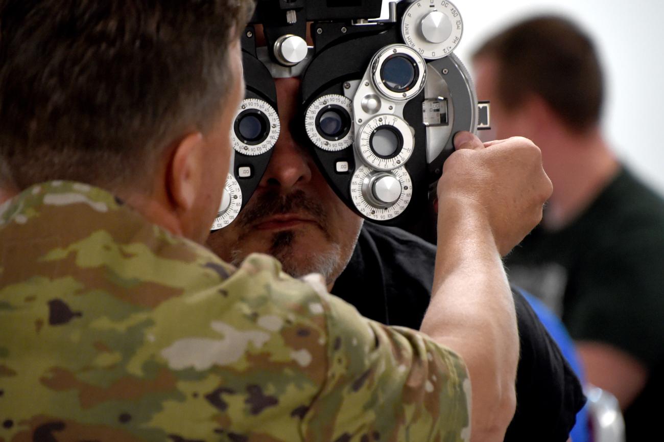 An optometrist from the National Guard gives an eye exam to a patient