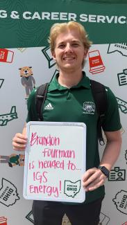 OHIO's COB student Brandon Fourman holding a sign saying he is going to IGS Energy for his summer internship.