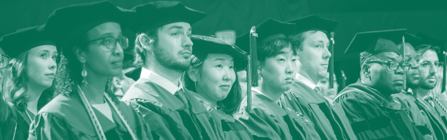A group of faculty in academic regalia sit in a row