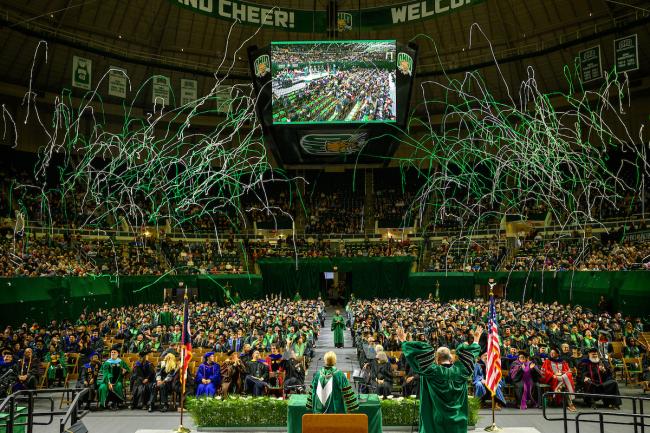 Green and white streamers explode over the 2025 fall Commencement ceremony