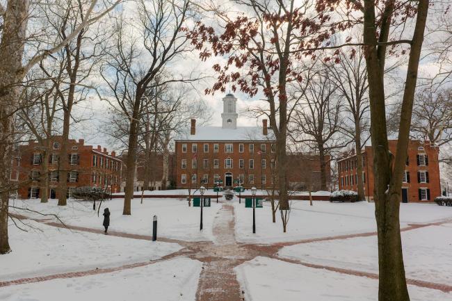 Cutler Hall and the College Green is covered with snow, but the brick paths have been cleared of snow and one person walks on a path.