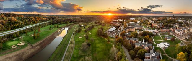 The OHIO campus, the Hocking River and the hills behind it are shown at sunset in Fall