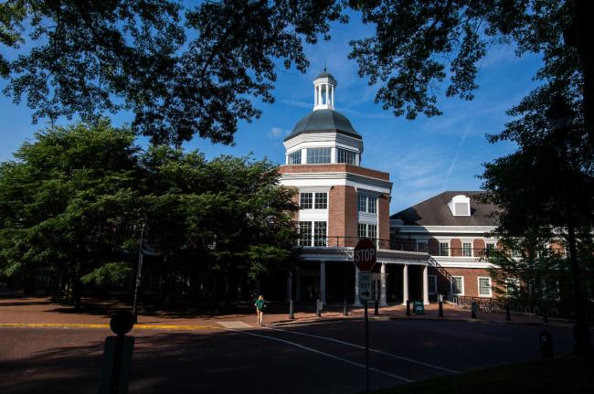 The fourth floor entrance of Baker Center is show on a summer day surrounded by green leaves on trees. An OHIO student walks across the brick street in front  of Baker Center.