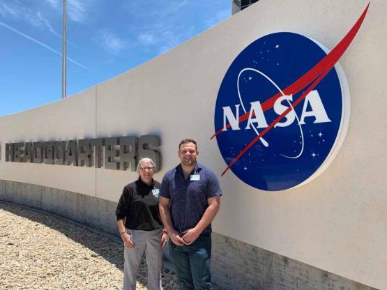 Dr. Sarah Wyatt and Dr. Alexander Meyers standing in front of the NASA Headquarters sign
