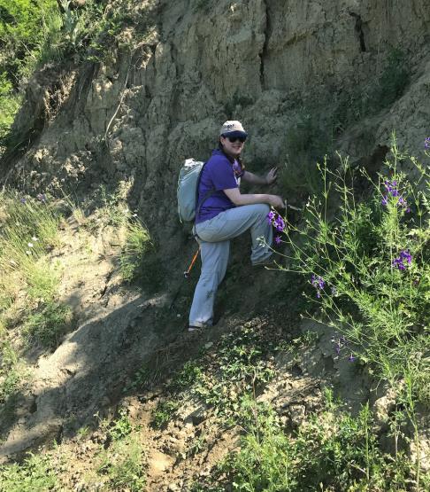 Dr. Sabrina Curran climbing up a hillside 