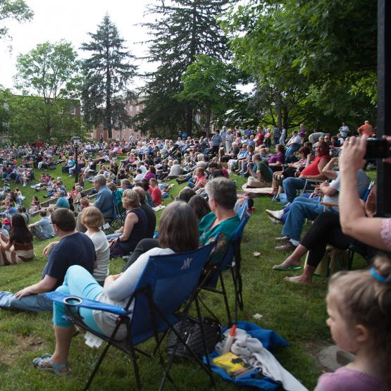 Crowd of people sitting in lawn chairs listening to music