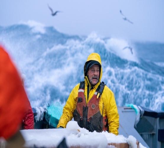 A crew member is shown in a fishing boat in the Bering Sea
