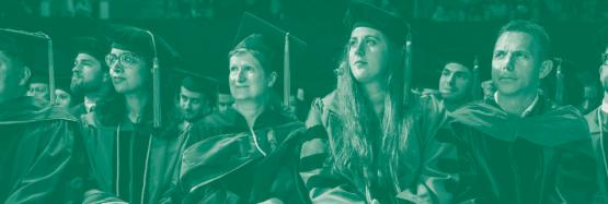 Faculty members dressed in academic regalia sit in an audience