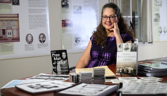 andrea Frohne sits at a table surrounded by artifacts from the African American Research and Service Institute
