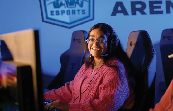 a female Ohio University student with long black hair and glasses wars a videoconferencing headset and sits in a computer chair
