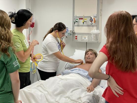 a student practices listening for a heartbeat in a nursing lab