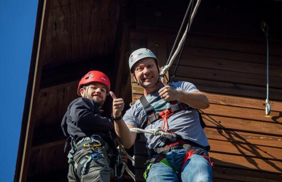An OHIO Dad and a student hold onto ropes while getting ready to zip line at Ohio University