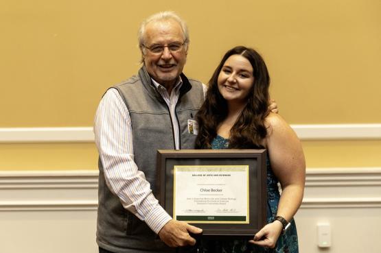 John Kopchick and Chloe Becker hold the award