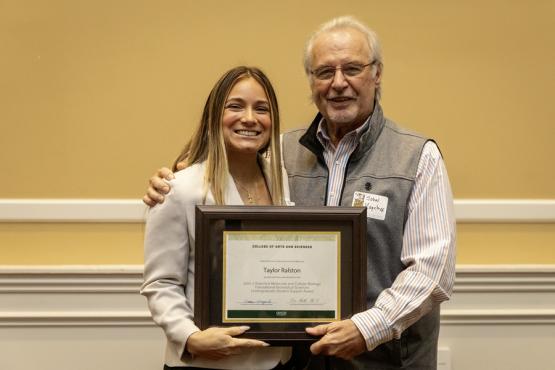 John Kopchick and Taylor Ralston hold the award
