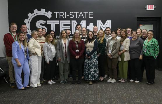 Individuals from regional STEM programs pose for a photo in front a wall that says Tri-State STEM