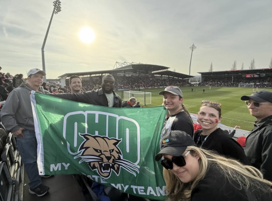 OHIO alumni and staff hold an Ohio University flag while at Wrexham Football Club game 
