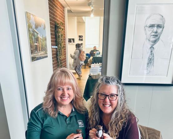 Two OHIO representatives hold small OHIO squirrel figures at the Social Work Resource Fair at Ohio University Lancaster