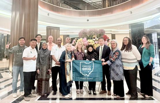 OHIO representatives and OHIO alumni hold a flag that says Forever OHIO - Proud Alumni while they are at an event in Kuala Lumpur, Malaysia