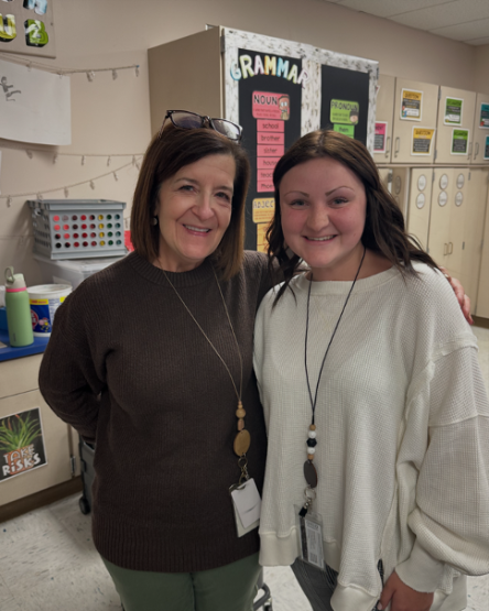 Two female teachers smiling, standing side by side in a elementary classroom