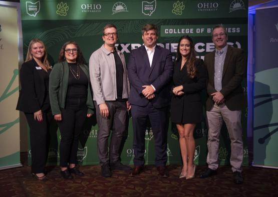 Representatives of the OHIO - LAIOB partnership stand together for a photo in front of an OHIO banner