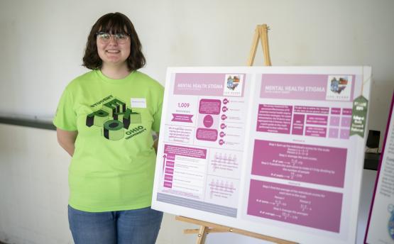 MacKenzie Kay stands beside a research poster