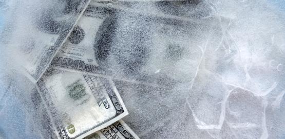 100 dollar bills frozen under a sheet of ice.